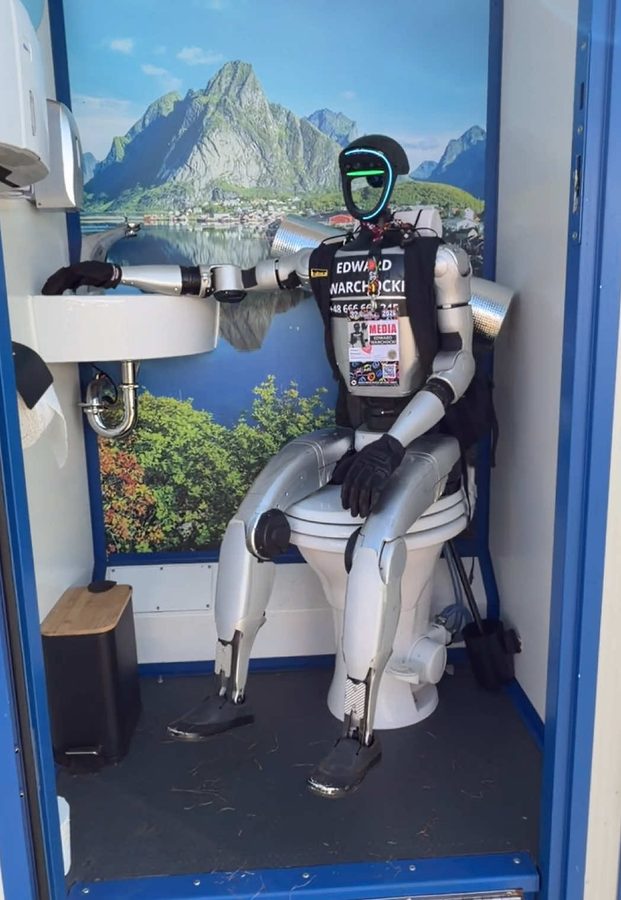 Edek seated inside a portable festival toilet