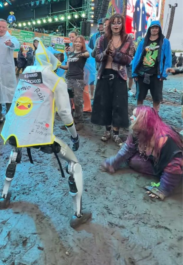 Edek in a decorated rain poncho walking through festival mud